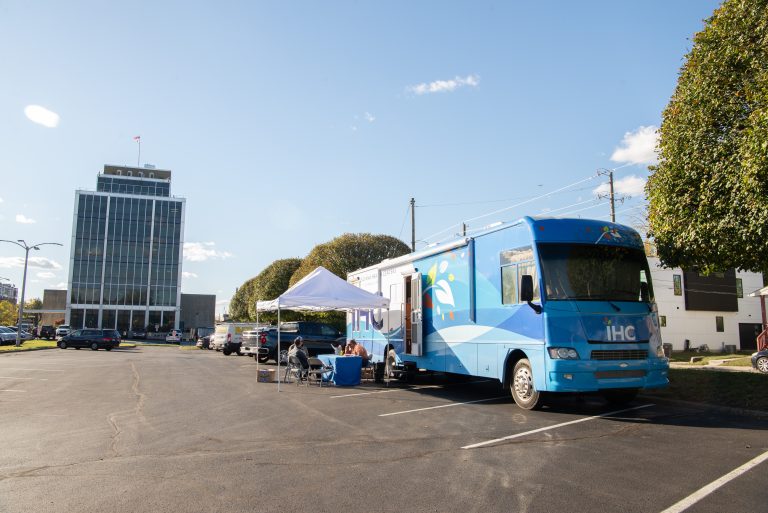 A mobile health unit parked with a tent in front of it.